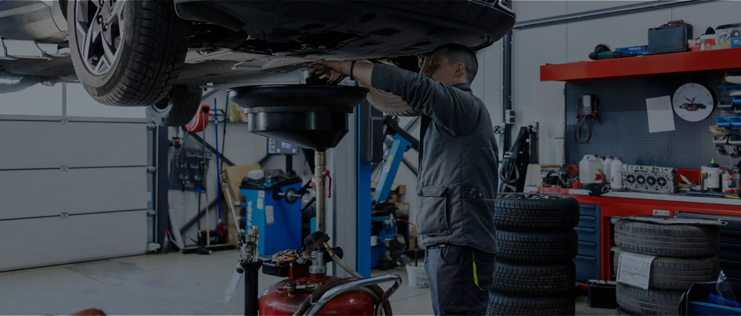 Mechanic performing vehicle oil change. Vehicle is on a lift while the mechanic is below with the oil catch pan